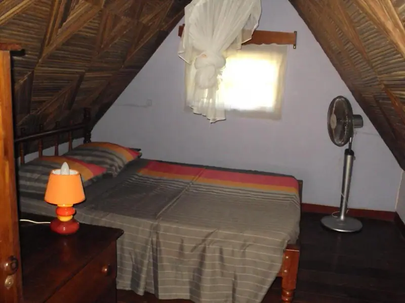 Chambre sous la charpente, lit et lampe de chevet