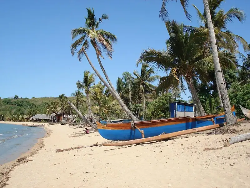 Pirogue à balancier bleue sur la plage d'Ambatoloaka, sous les cocotiers